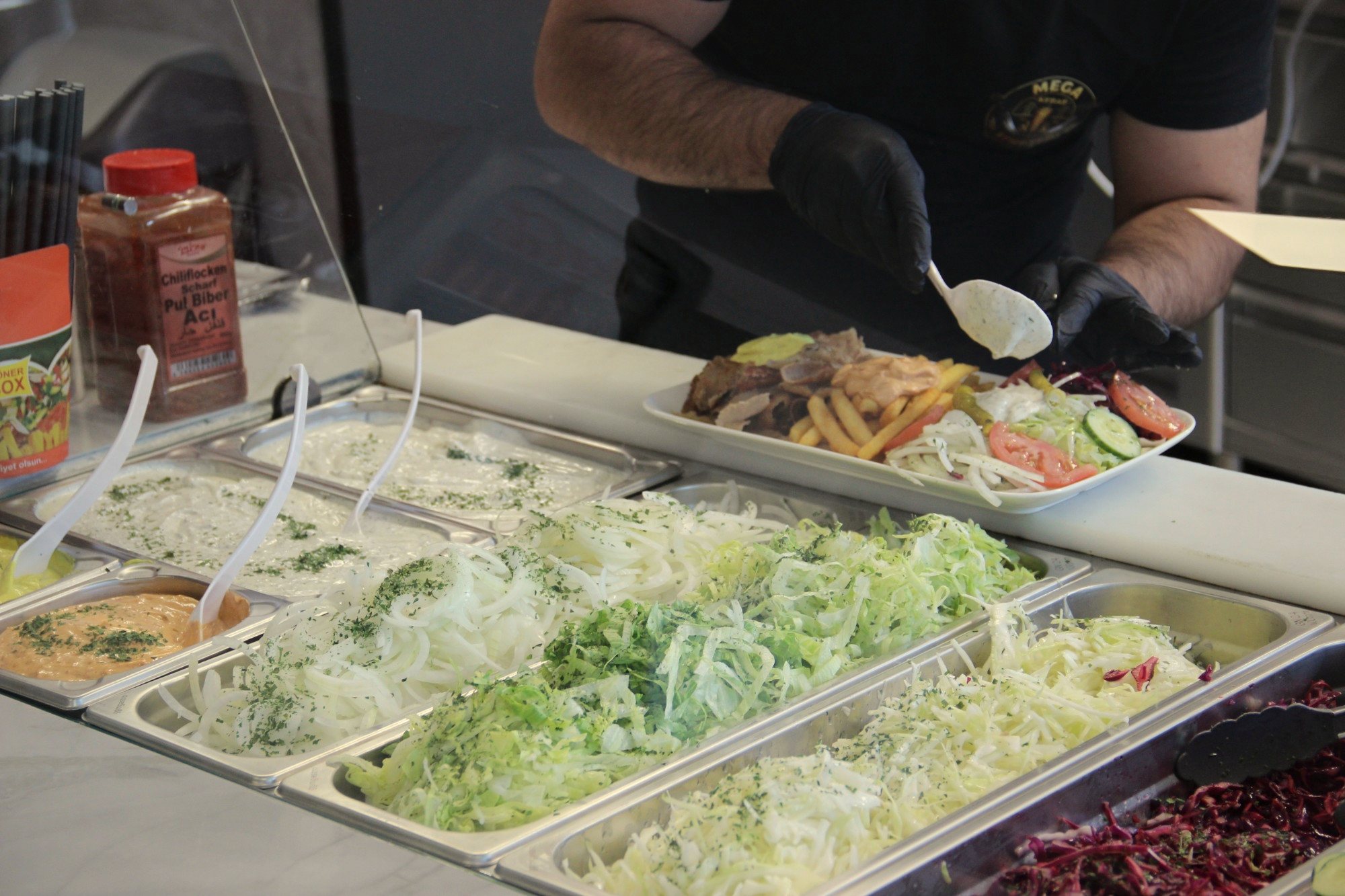 Mitarbeiter von Mega Kebab Kempten richtet frischen Dönerteller mit Salat an